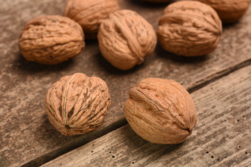 Walnut kernels and whole walnuts on rustic old oak table.
