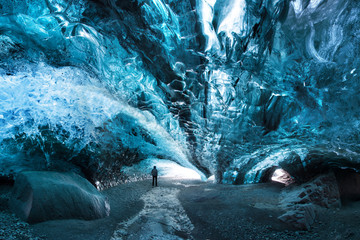 Man silhouette in ice cave. Blue crystal ice cave and an underground river beneath the glacier. Amazing nature of Skaftafell, Iceland. Vatnajokull National Park