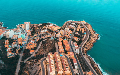 Beautiful mediterranian coastline near Valencia, Spain with small town, hotels, buildings and roads. Autumn winter blue turquoise cold sea water and warm colors coastline. Aerial drone shot view