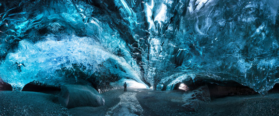 Man silhouette in ice cave. Blue crystal ice cave and an underground river beneath the glacier. Amazing nature of Skaftafell, Iceland. Vatnajokull National Park