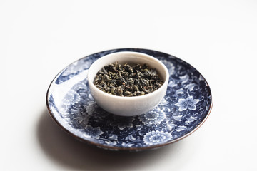 chinese tea in a drinking bowl on the old ceramic blue plate on white background