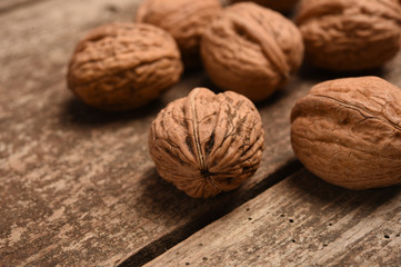 Walnut kernels and whole walnuts on rustic old oak table.