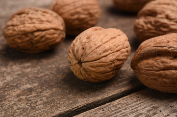 Walnut kernels and whole walnuts on rustic old oak table.