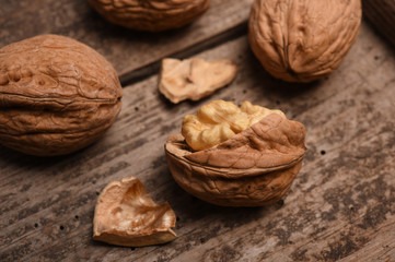Walnut kernels and whole walnuts on rustic old oak table.