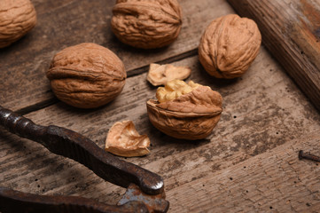 Walnut kernels and whole walnuts on rustic old oak table.