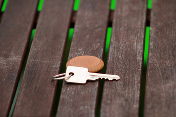 Hotel suite key with wooden fob for room on wood table. Room key on wood texture and background. Silver key with a blank label on an old wooden plank. Security and key in hand. Key of my success.