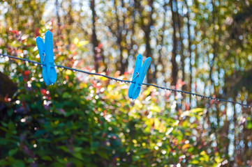 Fototapeta na wymiar Two blue clothes pegs hanging on a metal string