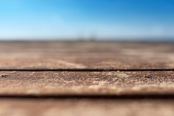 Empty natural wooden table background shot at a very short depth of field showing rustic sea swept wooden planks on a tropical caribbean beach walk way with sand dusted over them
