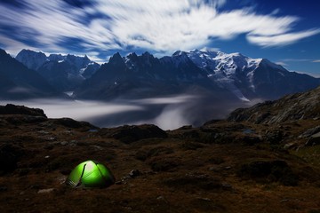 A panoramic view on Chamonix valley from in summer starry night. The area is the stage of the popular Mont Blanc Tour, France. Night scene with tent in Alps mountain. Beautiful sunny day in Alpes. - S