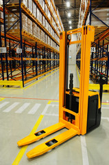 Yellow forklift in warehouse, industrial storage racking in background © asafaric