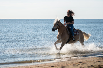 Fototapeta na wymiar girl riding on haflinger horse in the sea