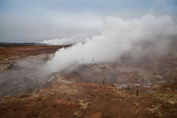 Desolate landscape of Iceland volcanic brown soil with steamy geyser mist