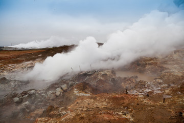 Desolate landscape of Iceland volcanic brown soil with steamy geyser mist