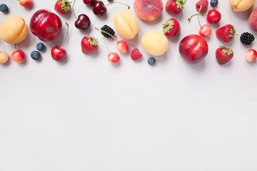 Variety of fresh juicy berries and fruits on grey background.