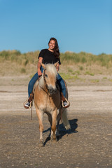 girl riding on haflinger horse on th beach