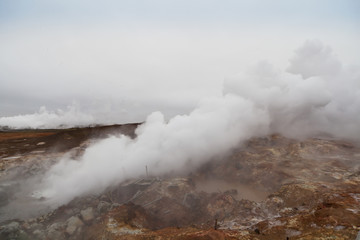 Fototapeta na wymiar Desolate landscape of Iceland volcanic brown soil with steamy geyser mist