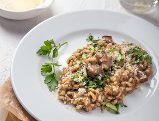 Italian food. Risotto with mushrooms and cheese on a white plate on a white background