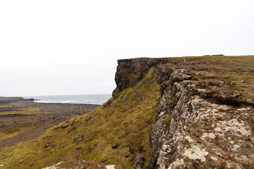 Fototapeta na wymiar Rocky cliff with grass on Iceland Reykjanes peninsula volcanic stones shore coast line
