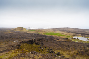Fototapeta na wymiar Iceland lighthouse Reykjanesviti with rocky volcanic soil gesers and grey sky
