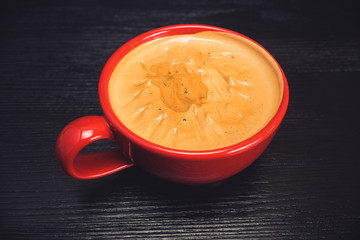 fresh aromatic coffee in a red mug on a black wooden background