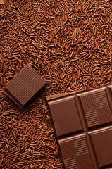 stack of dark chocolate broken in pieces over chocolate cacao sparkles 