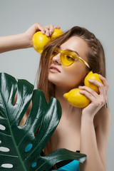 Beautiful fitness women in yellow sunglasses holding lemons near head