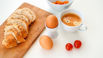 Pyszne i zdrowe śniadanie. Jajka, pocięta bułka, pomidorki i kawa