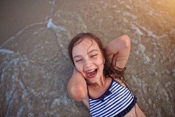 young girl laughs at the beach in the water