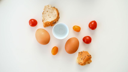 Jajka na miękko, pokrojone pieczywo i pomidorki koktajlowe na białym tle