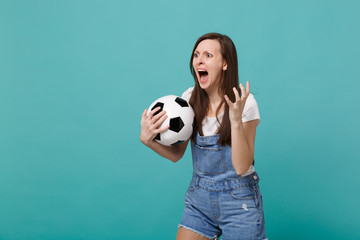 Angry screaming shocked young woman football fan support favorite team with soccer ball swearing looking aside isolated on blue turquoise wall background. People emotions sport family leisure concept.