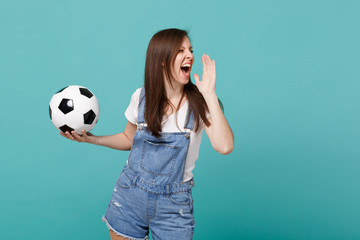 Crazy young girl football fan cheer up support favorite team with soccer ball screaming with hand gesture isolated on blue turquoise background in studio. People emotions sport family leisure concept.