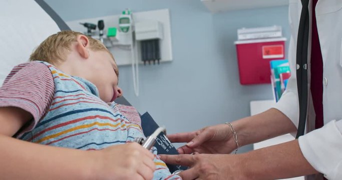 Little boy patient in pediatric office using blood pressure cuff on his own arm. Doctor showing child how blood pressure cuff works. Slow motion 4k