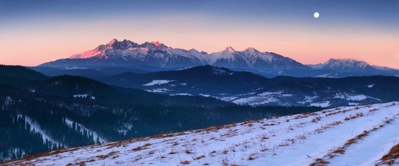 Panoramic view of beautiful winter wonderland mountain scenery in evening light at sunset....