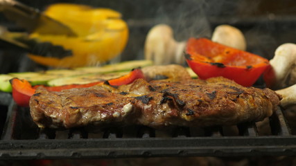 Slow motion of sirloin steak turned on flaming grid. Slow dolley movement