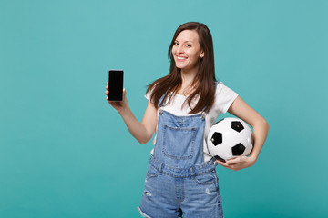Smiling woman football fan holding soccer ball, mobile phone with blank empty screen isolated on...