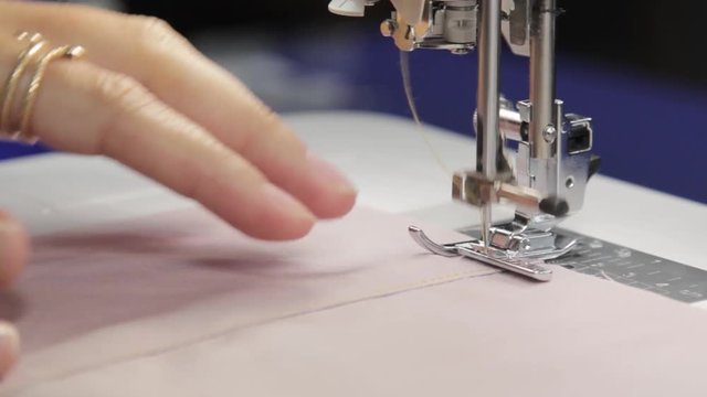 Tailor sews lingerie on a sewing machine, thread and lace, handmade underwear and clothes, sewing machine at work process, work in a sewing studio