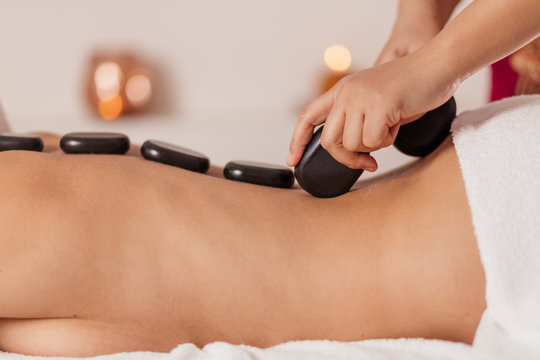 stone therapy in the spa salon.woman with hot basalt stones on her back lying on the bed in the beauty salon . close up cropped photo
