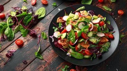 Fototapeten Traditional fattoush salad on a plate with pita croutons, cucumber, tomato, red onion, vegetables mix and herbs © grinchh