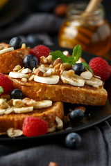 French cinnamon toast with blueberries, raspberries, banana, nuts, hazelnut and honey.