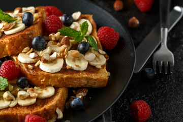 French cinnamon toast with blueberries, raspberries, banana, nuts, hazelnut and honey.