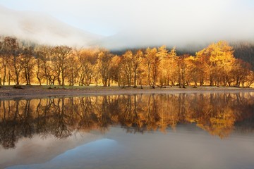 Scottish Loch in the early morning. A very calm autumn day at Loch Voil, near Balquhidder in the Loch Lomond and Trossachs National Park, Scotland. Beautiful landscape reflection in water.