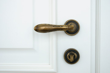 Vintage metal handle and keyhole in a wooden white door