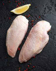 Raw duck breast with seasonings on rustic black background
