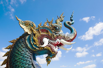 Fototapeta na wymiar The head of a dragon against a blue sky. Buddhist temple Wat Rong Seur Ten (Blue Temple). Chiang Rai, Thailand