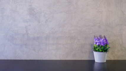 artificial purple plant in the pot for decorate on the table and cement wall background with copy space