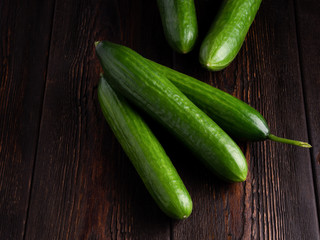 cucumbers on dark brown wooden background.