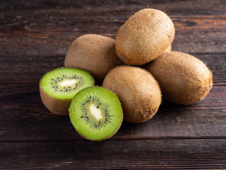 Kiwi on dark brown wooden background.