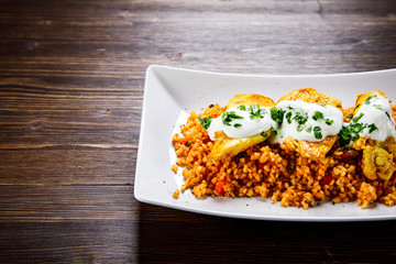 Grilled chicken meat with groats and vegetables on wooden table