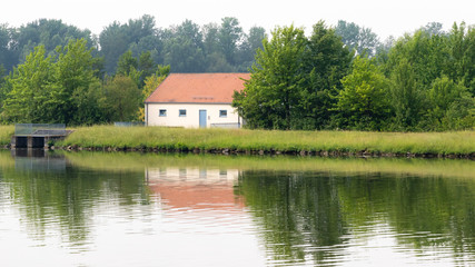Water pump house next to a river with a red roof
