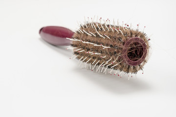 Comb full of hair lossed. Lots of hair on the hairbrush close up on a white background.